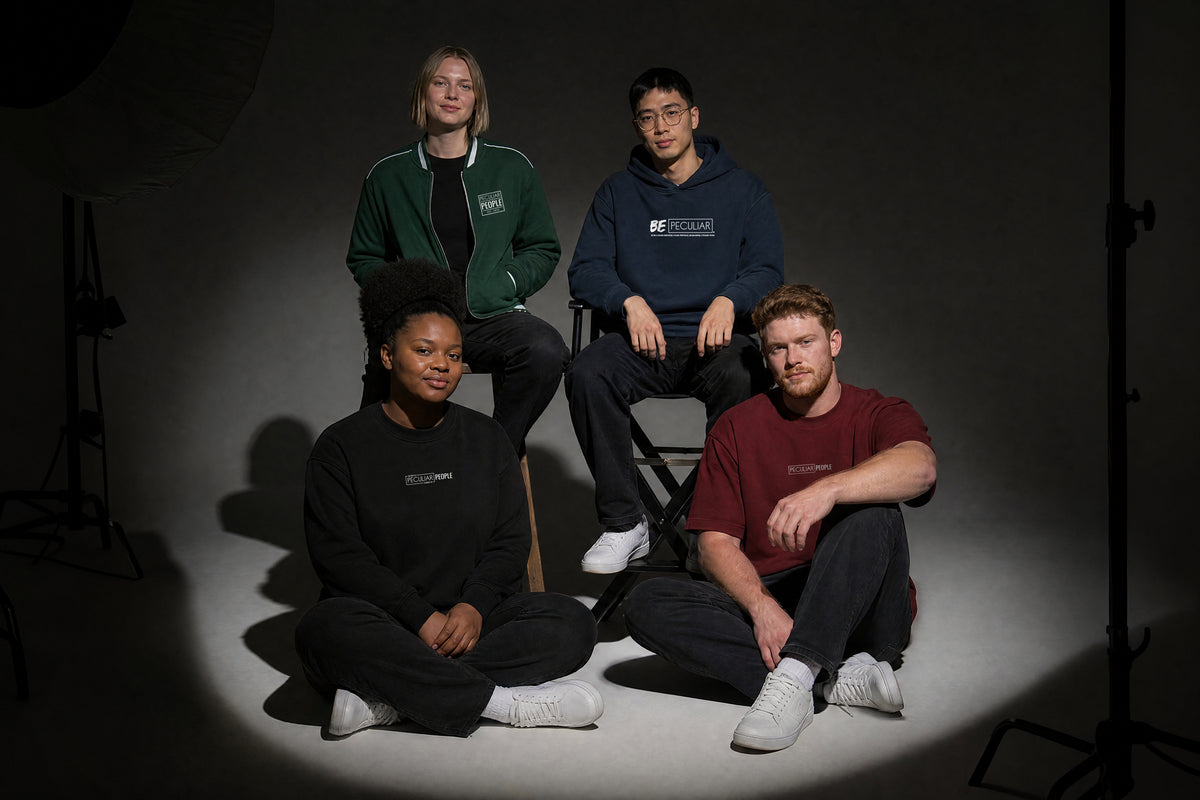 Four friends in a studio: a forest green bomber jacket, a navy hoodie, a black sweatshirt and a maroon tee